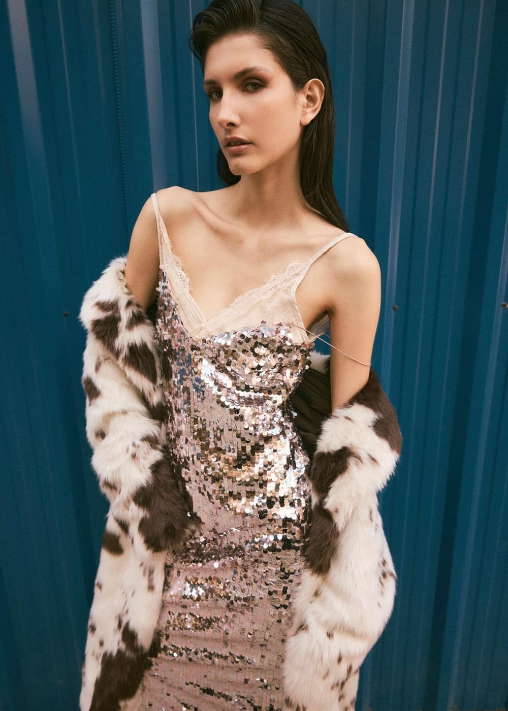 Editorial Angels: modelo con vestido de lentejuelas y tapado frente a una cortina azul